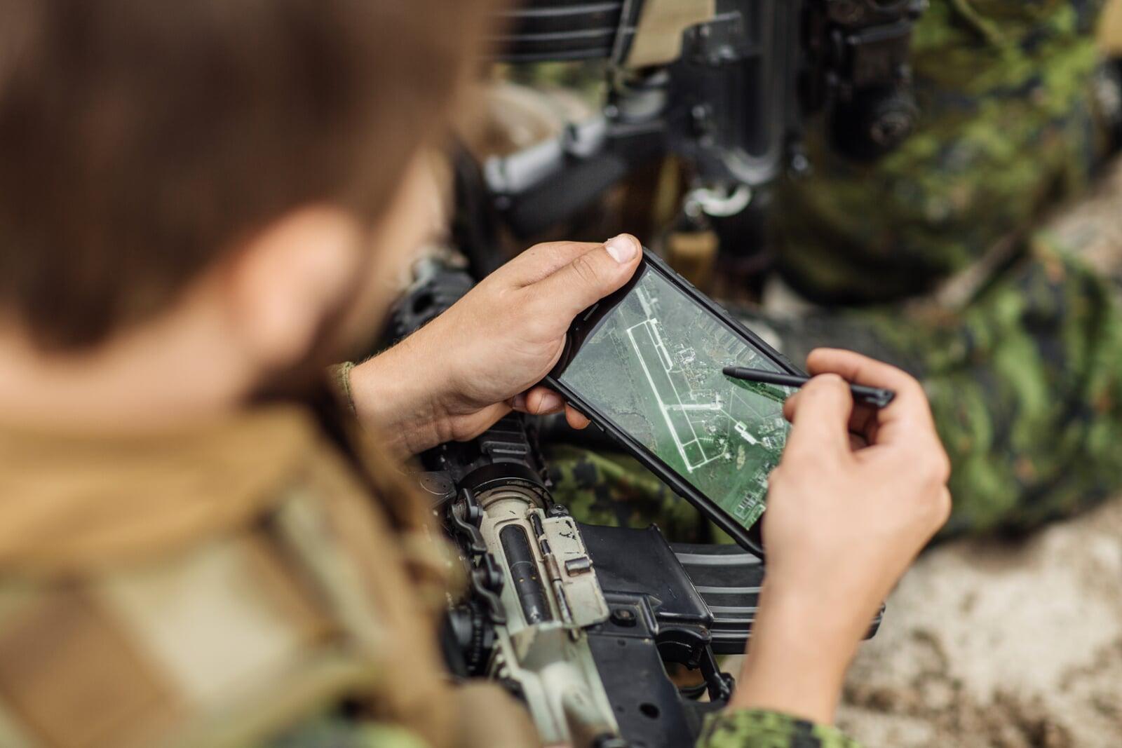 A service member using a rugged tablet in the field